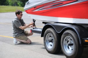 A Man Adjusting Tie Down Straps On Boat Trailer