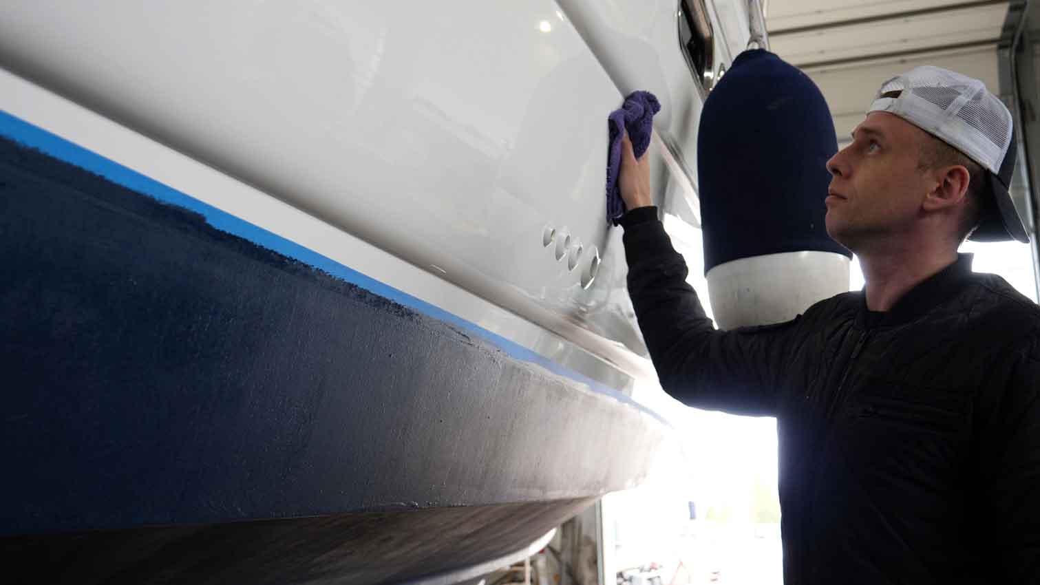 worker-polishing-a-boat-in-storage Professional male marina worker polishing a boat in storage